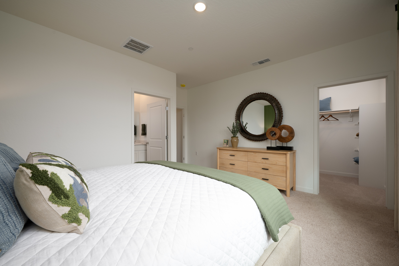 A bedroom with a bed and a mirror.