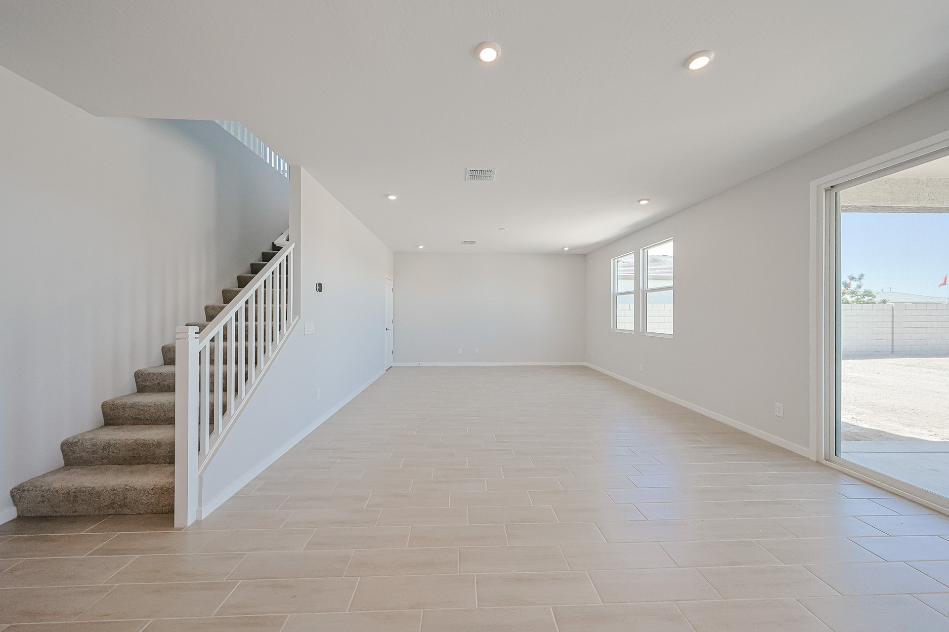 A large white room with a glass door and a white staircase.