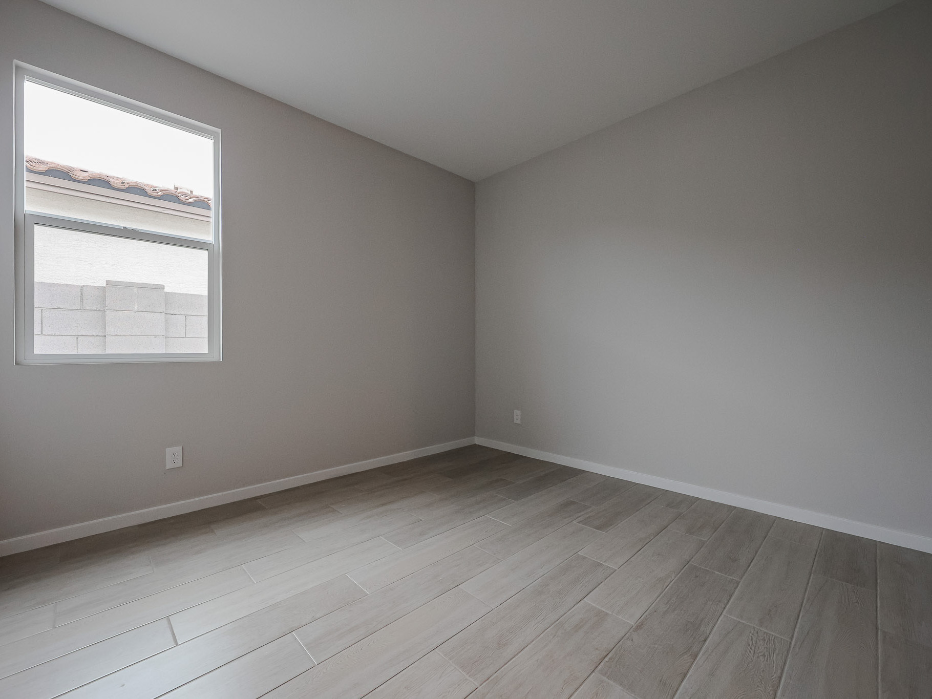 A room with a wood floor and a white wall with a painting on it.