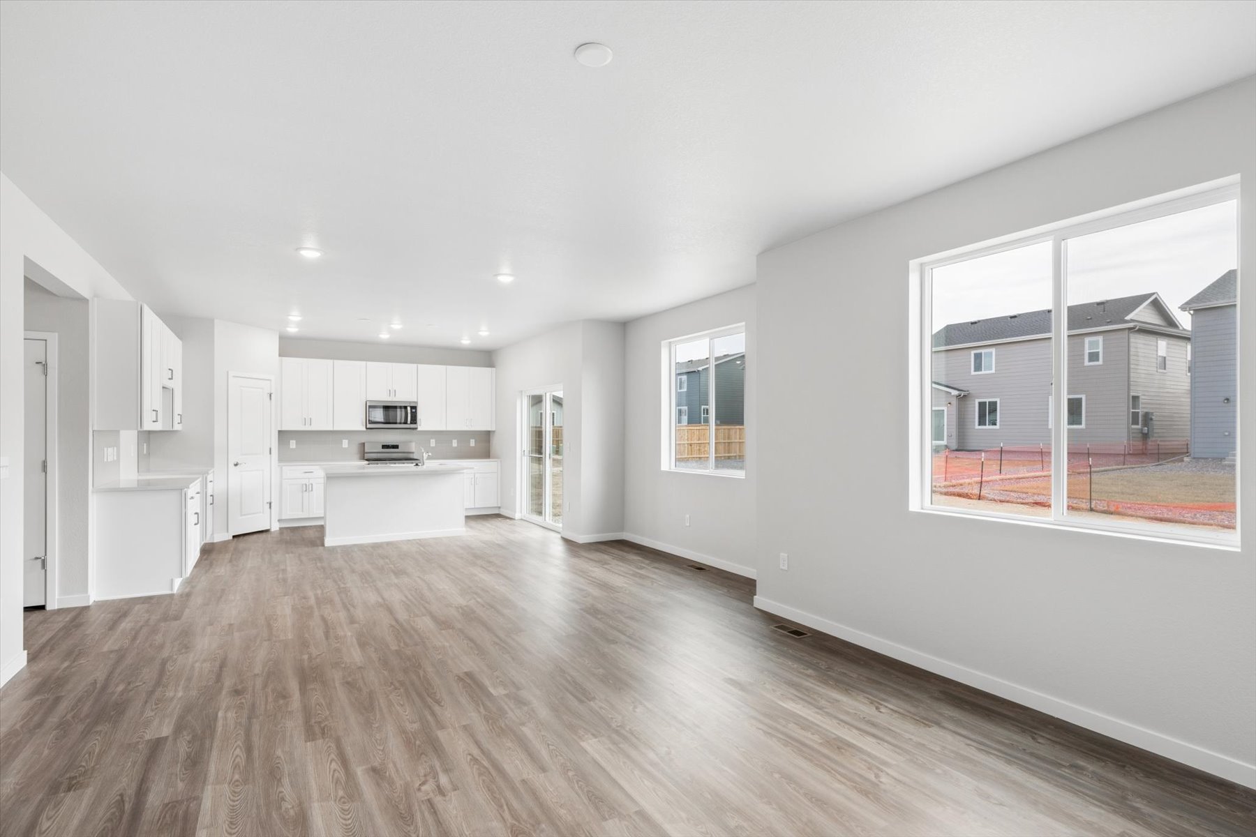 A large white room with a wood floor and a large window.