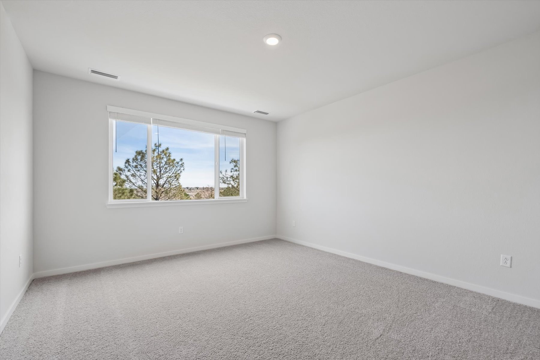 A room with a window and a white wall.