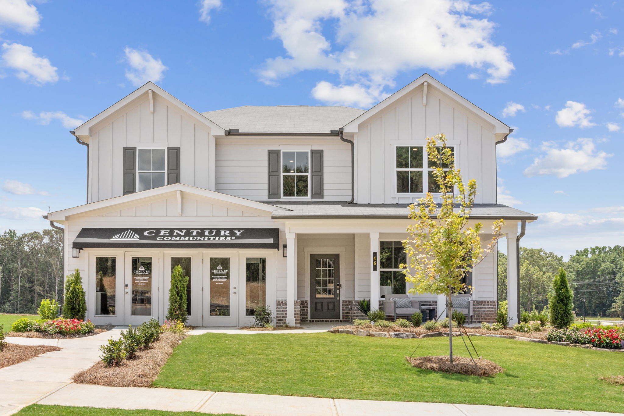 A white house with a lawn and trees in front of it.