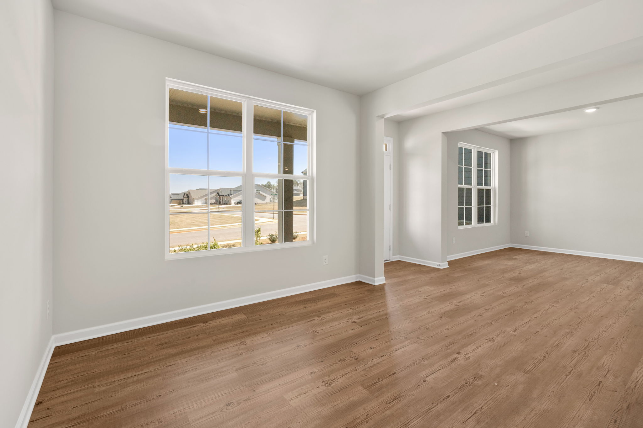 A room with a wood floor and a window with a view of the water.