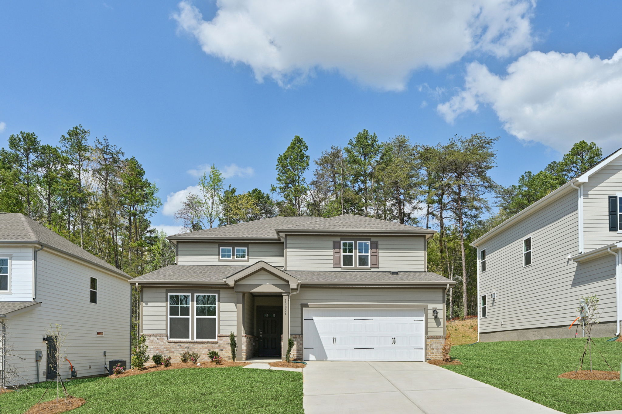 A house with a garage and trees in the back.