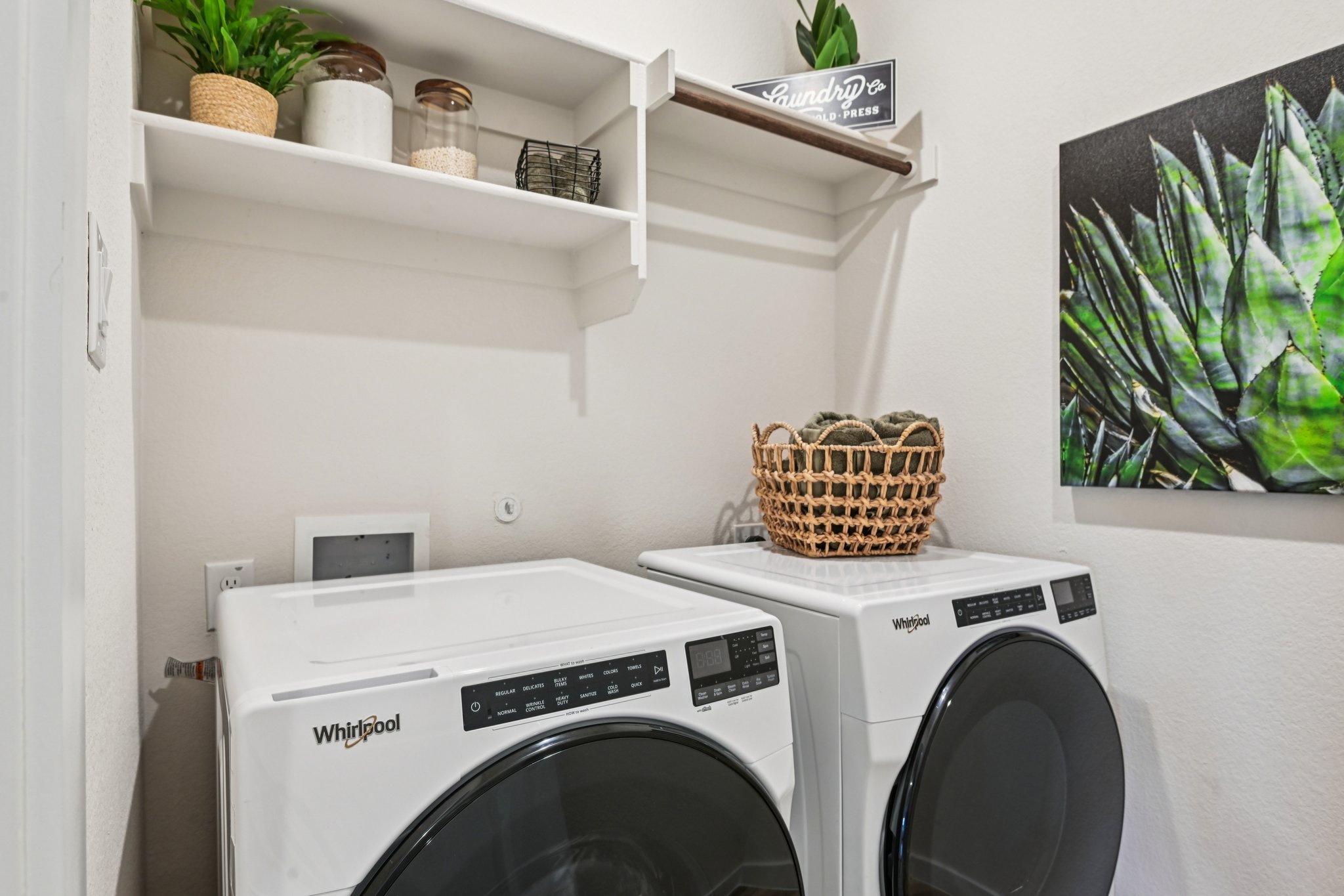 A white laundry room with a white laundry machine and shelves.
