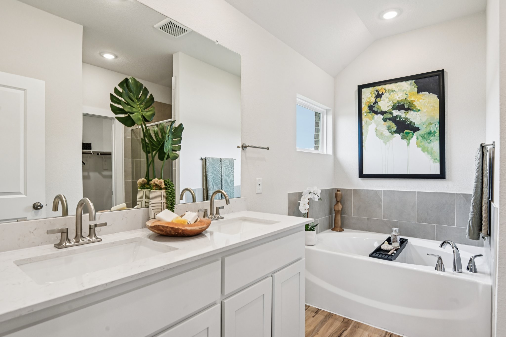 A bathroom with a tub sink and a mirror.