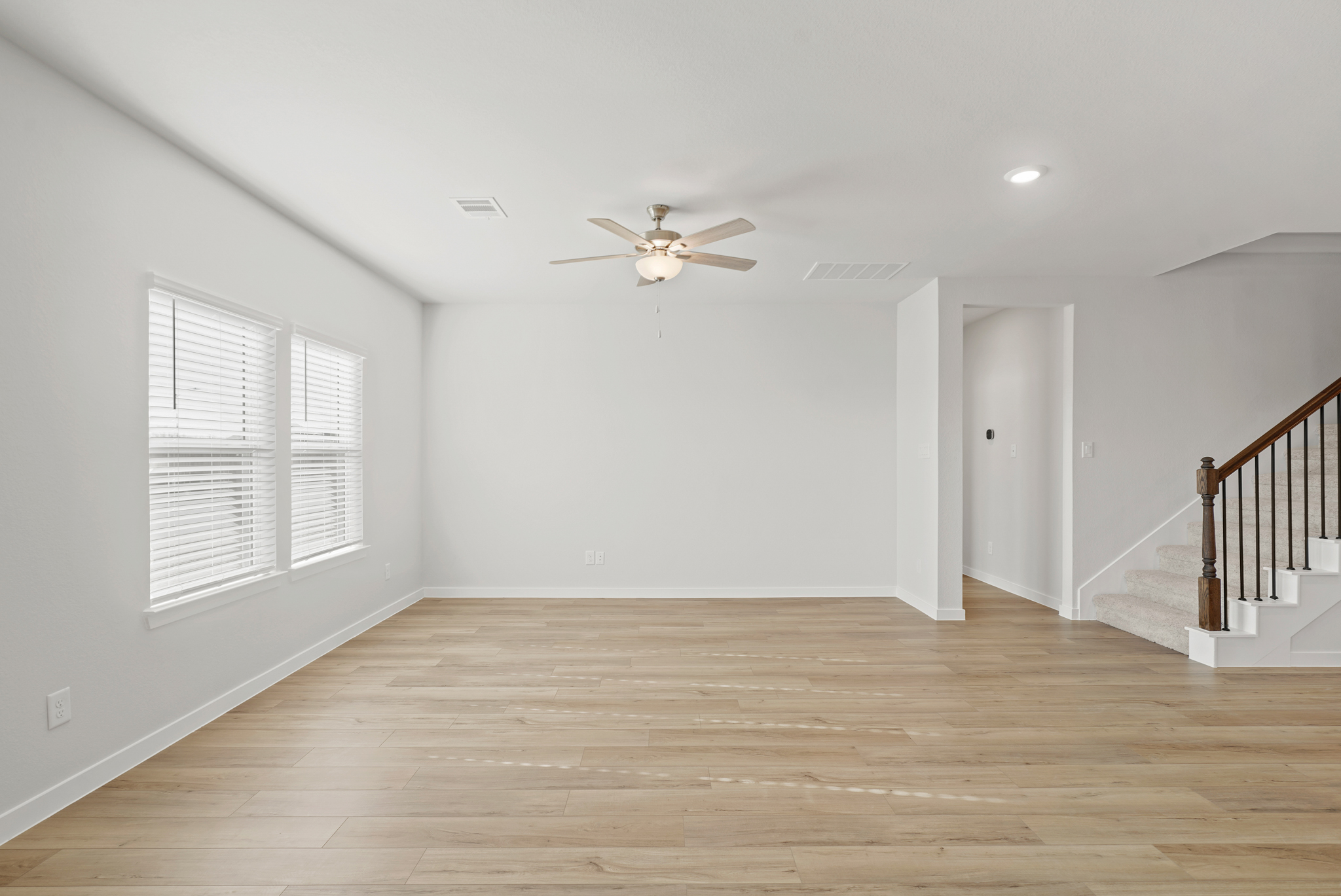 A room with a wood floor and a ceiling fan.