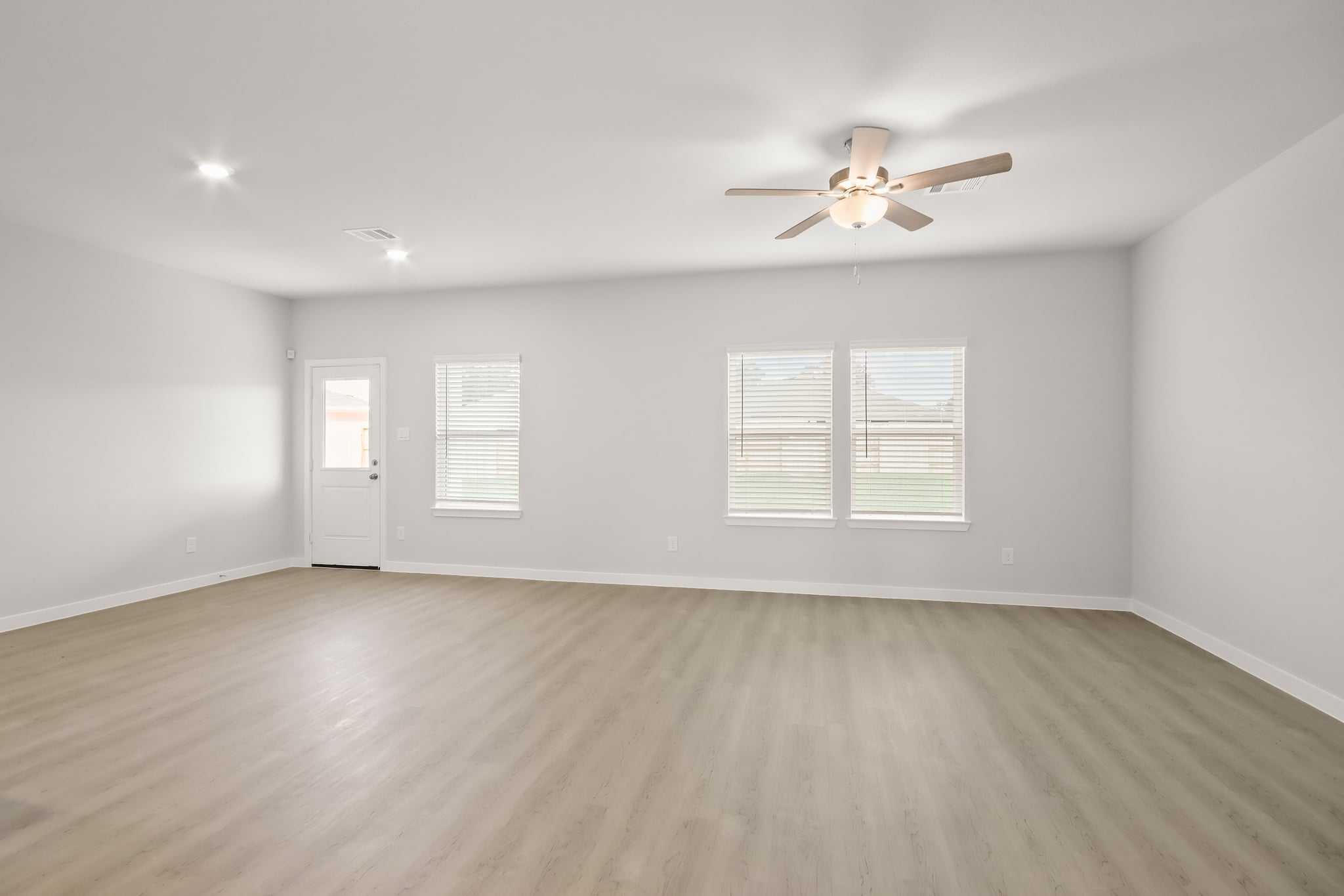 A room with a ceiling fan and a wood floor.