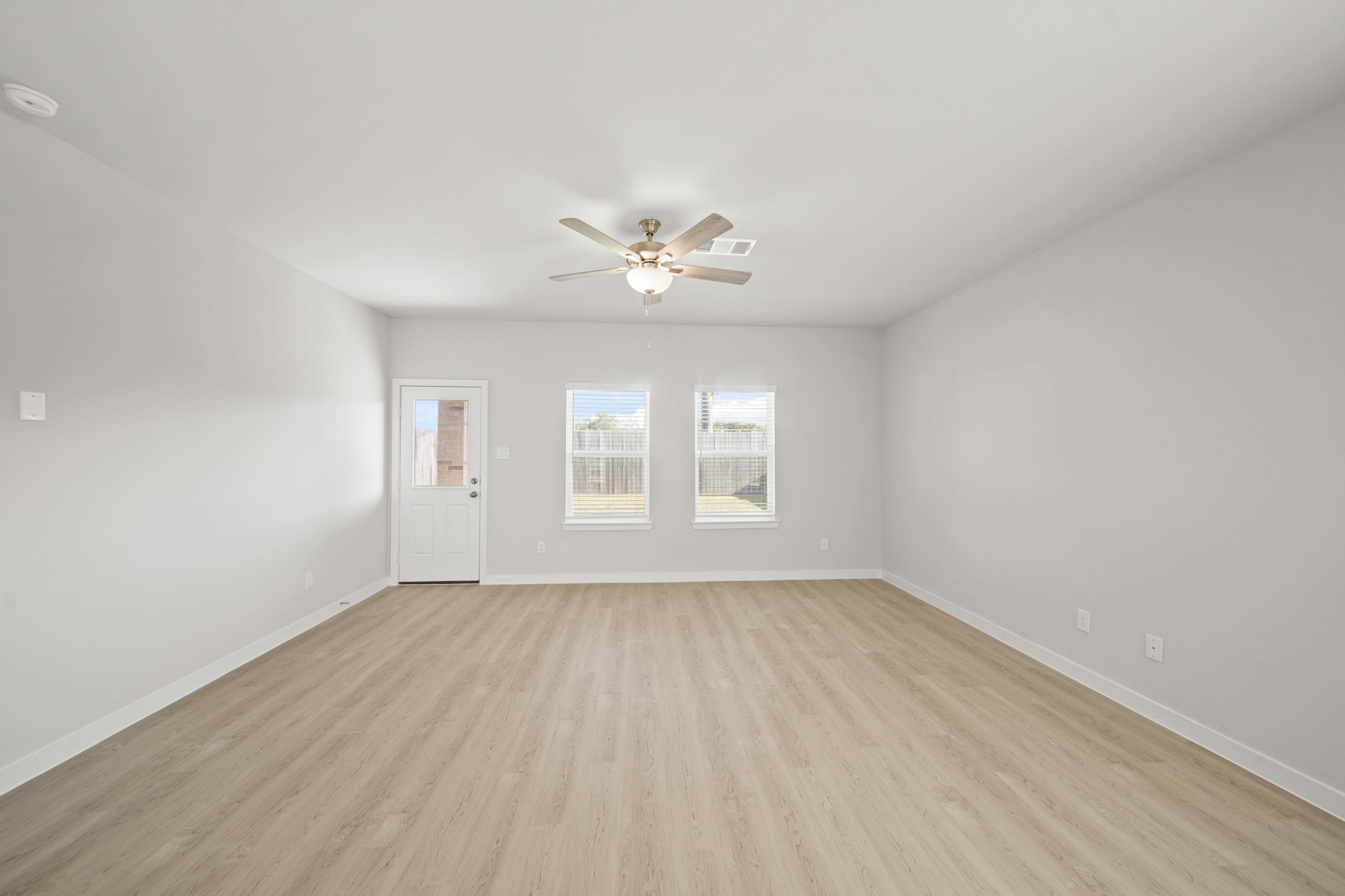 A room with a ceiling fan and a wood floor.