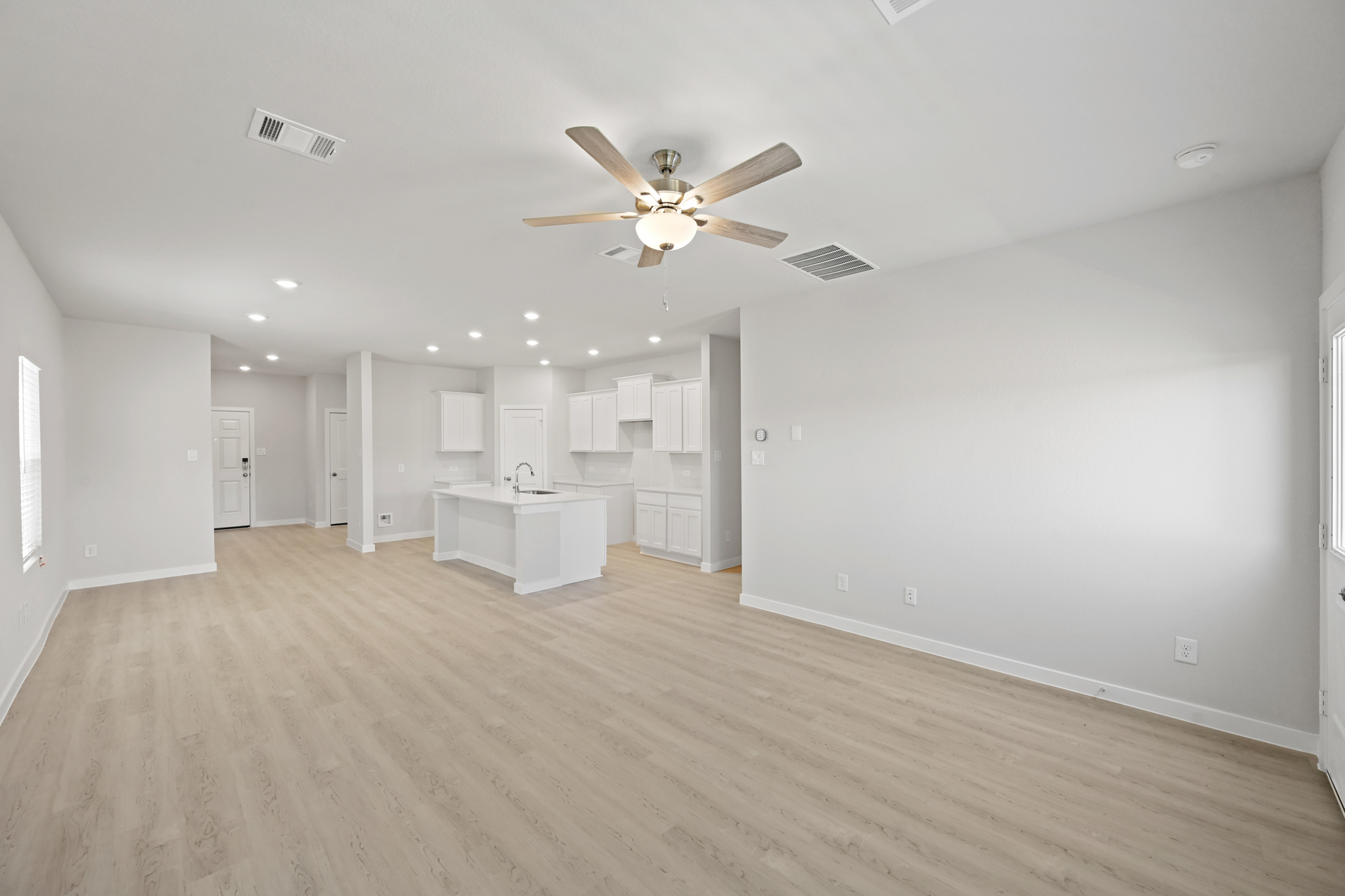 A large empty room with a ceiling fan and a wood floor.