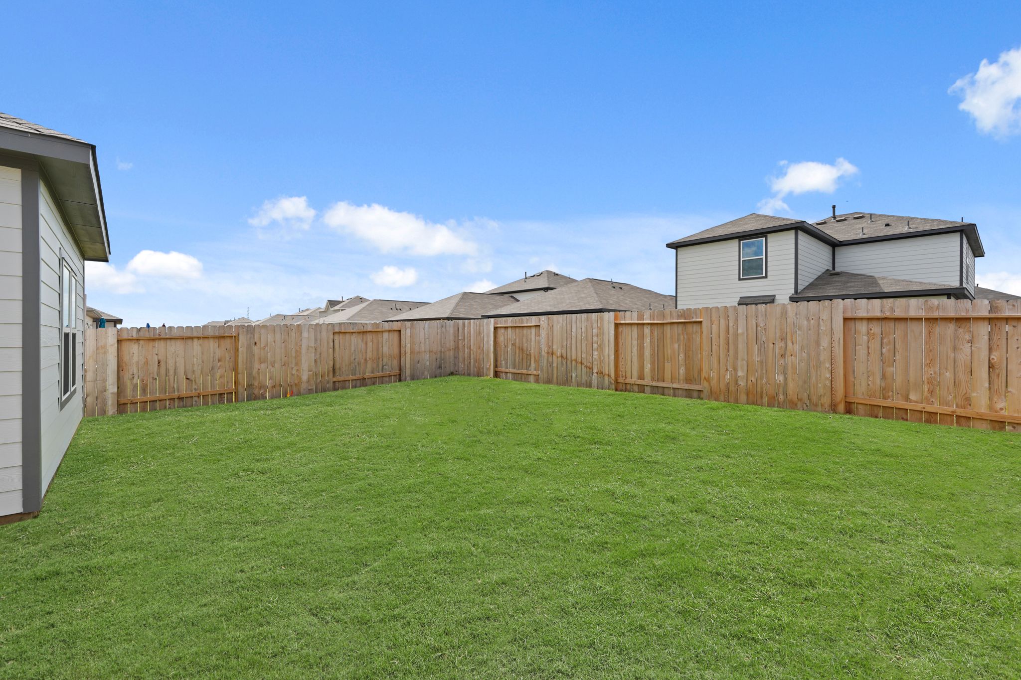 A fenced in yard with a house in the background.