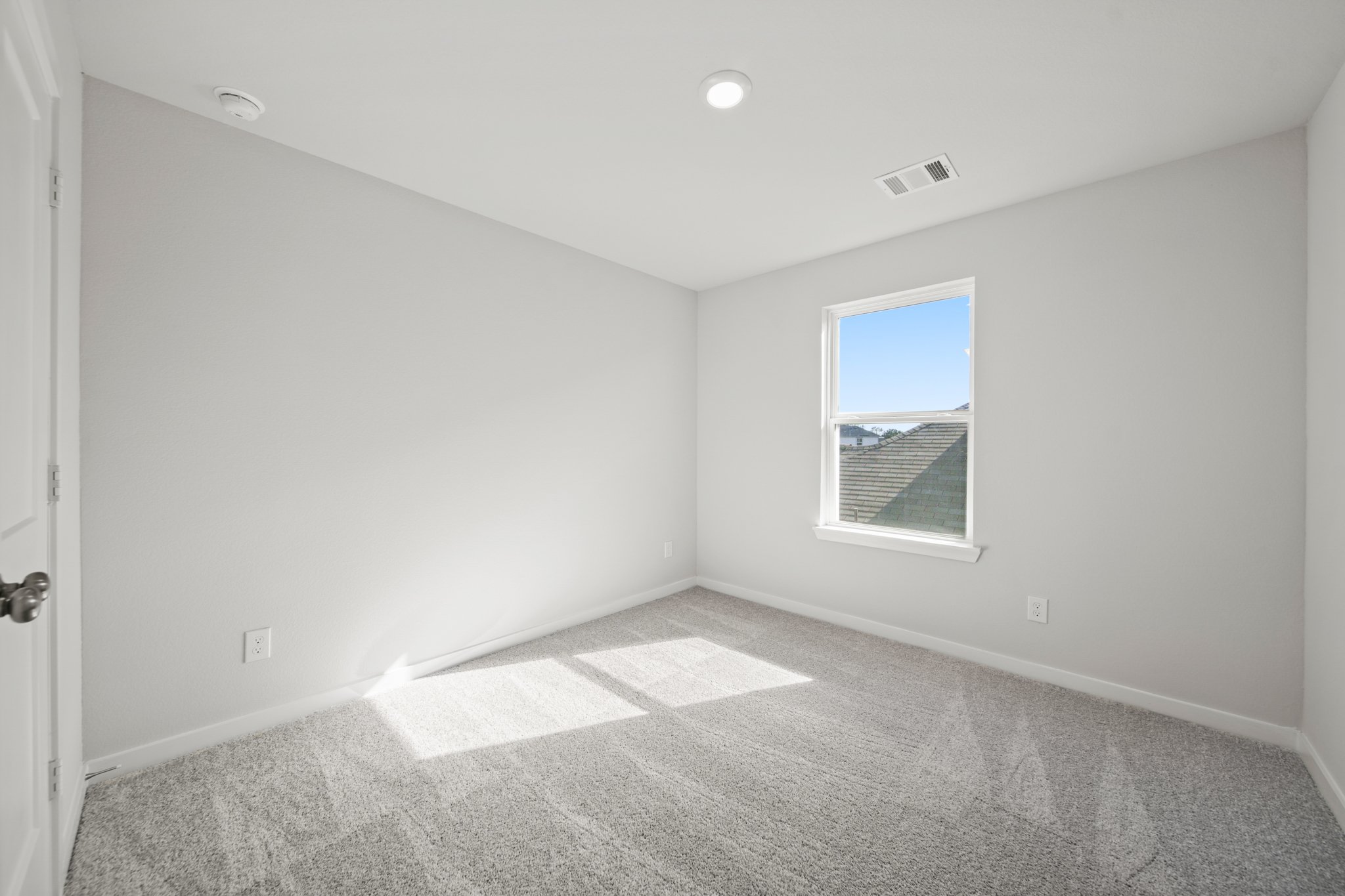 A room with a window and carpet.