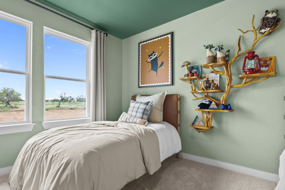 A bedroom with a bed and a shelf with art on it.