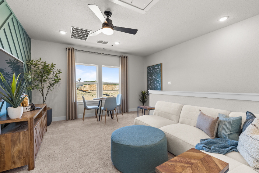 A living room with a couch and a fan.