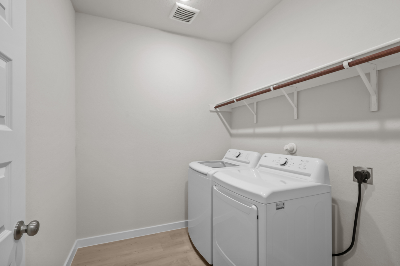 A white laundry room with a white shelf and a white wall.