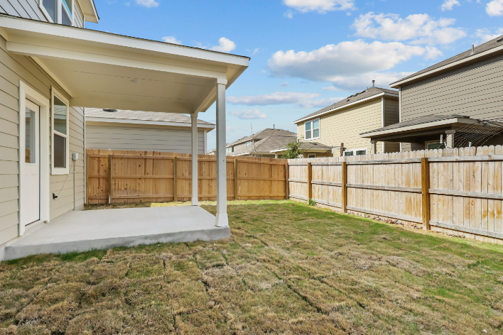 A fenced in yard with a house in the background.