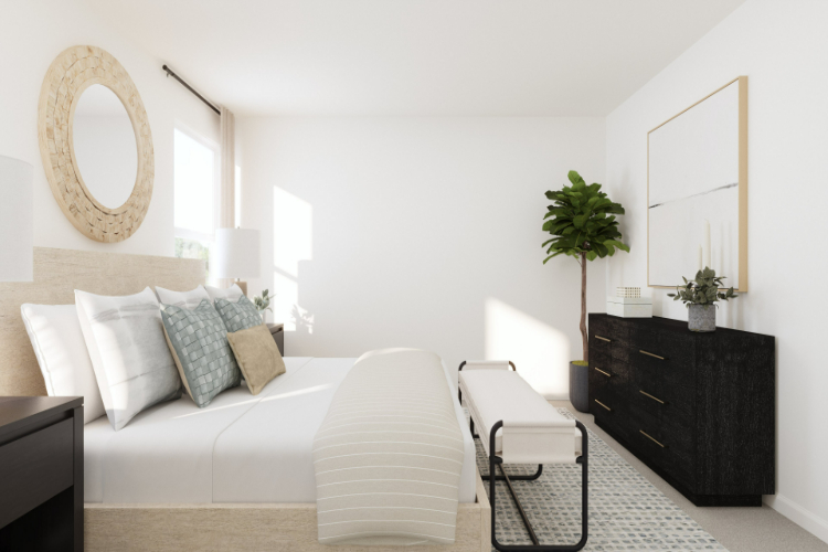 A room with a white couch and a table with a plant on it.