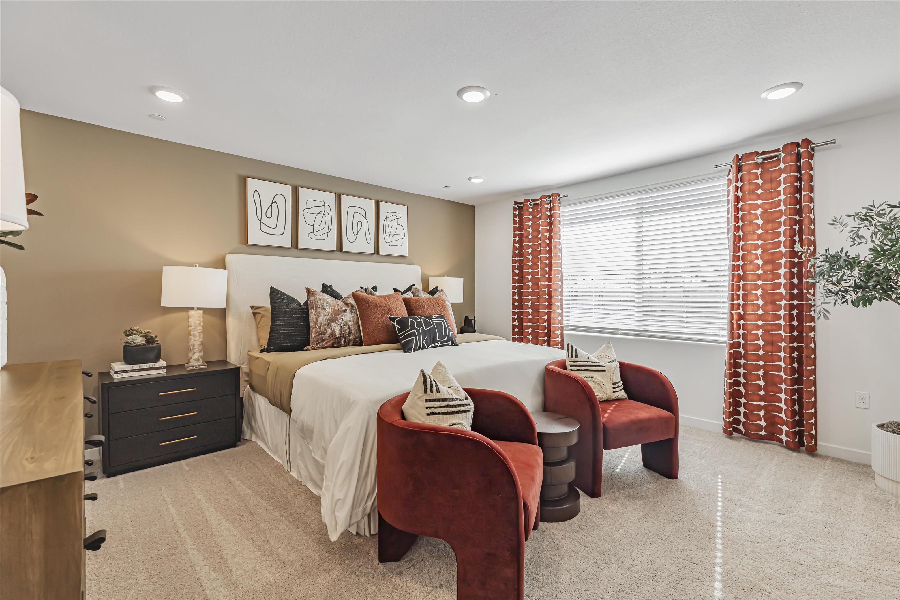 A bedroom with a bed and chairs.